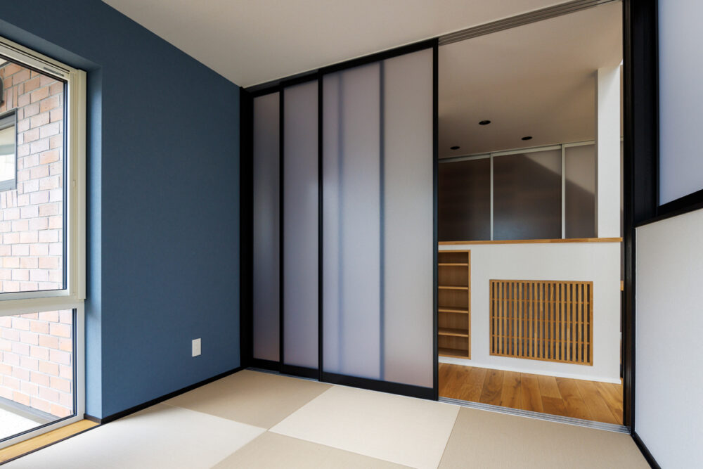 LDKの一角には、多目的に利用でき、個室にもなる和室を配した。ブルーの壁紙がシンプルな空間のアクセントに